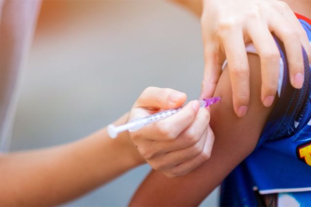 Adult administering vaccination on child's arm